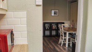 A kitchen with white cabinets, a red appliance, and a wooden floor.