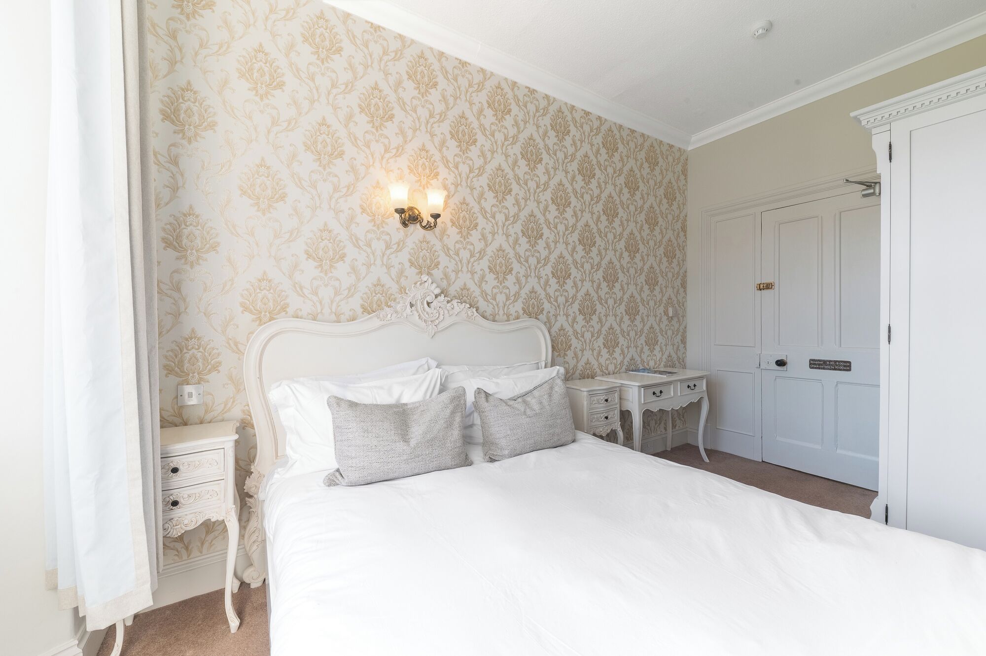 Une chambre à coucher avec un grand lit, une table de chevet, une commode et une porte.