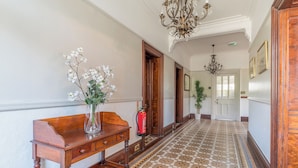 A hallway with a wooden bench, a vase with flowers, a fire extinguisher, and a patterned floor. - Fir Trees (Windermere)