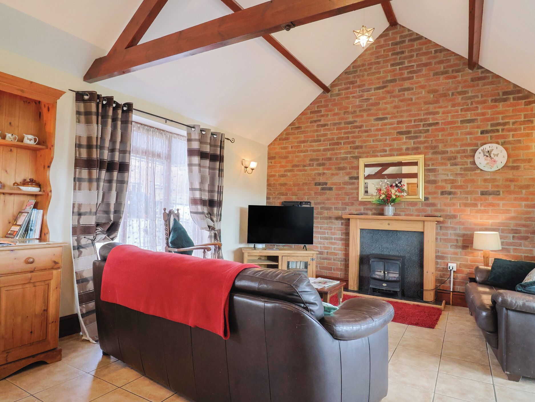 A cozy living room with a fireplace, a television, and a leather sofa.