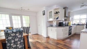 Una cocina moderna con armarios blancos, una mesa de comedor de madera y sillas.