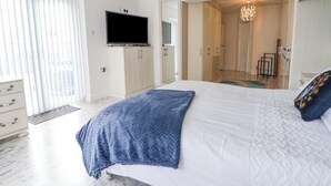 Un dormitorio moderno con una cama grande, un televisor de pantalla plana y un vestidor.