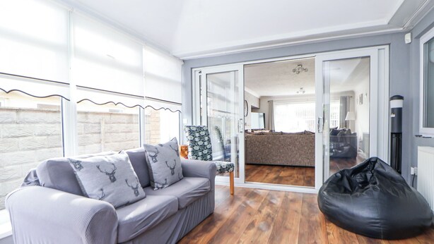 Una sala de estar moderna con un sofá gris, un sillón informal negro y piso de madera.