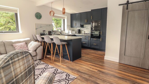 A modern kitchen with dark cabinets, a central island, and a sliding barn door. - Hogans Cottage (Ennistimon)