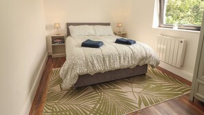 A bedroom with a bed, two bedside tables, a window, and a radiator. - Hogans Cottage (Ennistimon)