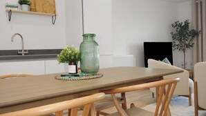 A modern kitchen with a wooden dining table, chairs, a green vase, and a small plant on the counter. - Wharfside (Penzance)