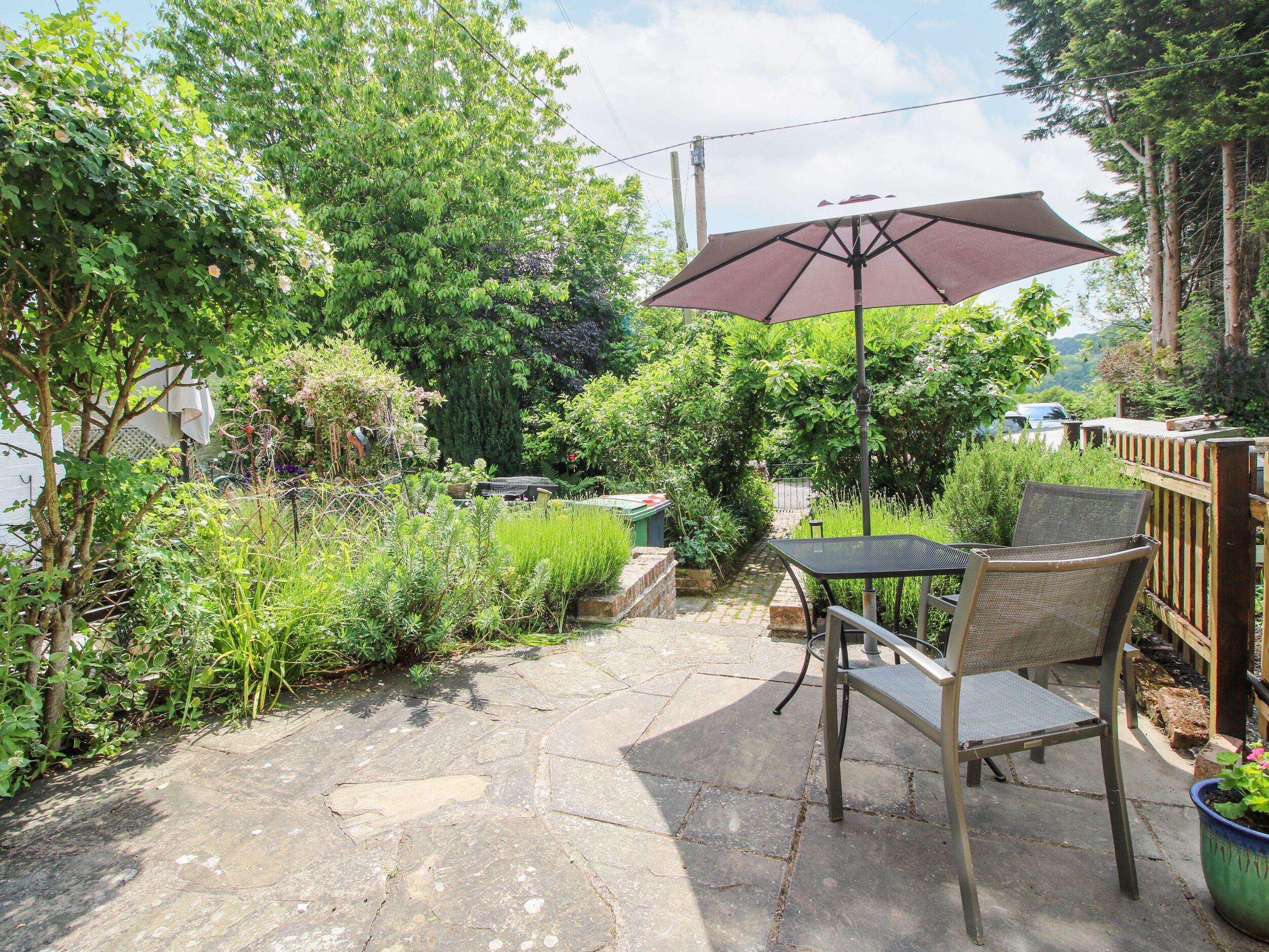 A patio with stone flooring, a table and chairs, and a large umbrella.