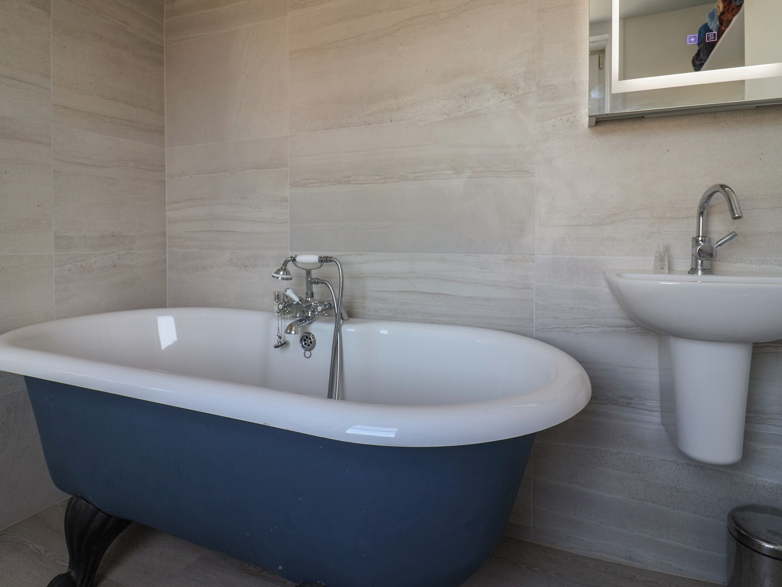 A bathroom with a freestanding bathtub, a sink, and a mirror.
