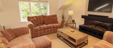 A living room with a sofa set, a coffee table, a fireplace, and a television.