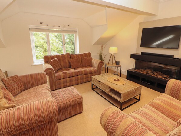 A living room with a sofa set, a coffee table, a fireplace, and a television.