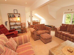 A living room with striped sofas, a red armchair, a wooden coffee table, and a bookshelf with books and a framed certificate. - Waterfall (Ambleside)