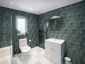 A modern bathroom with a toilet, sink, and shower area. - Bay View (Redruth)