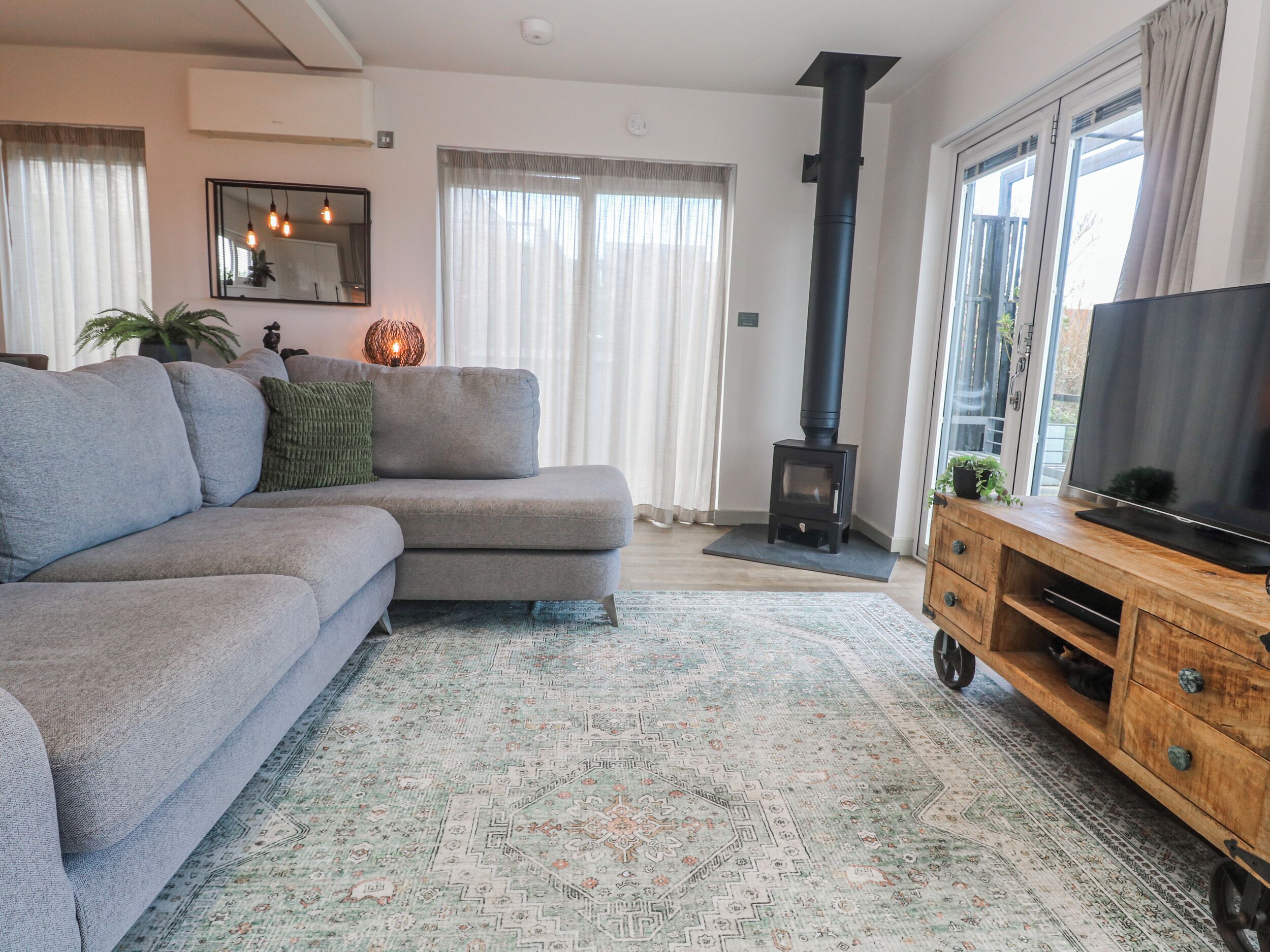 A living room with a sofa, a television on a wooden stand, a fireplace, and a large window.