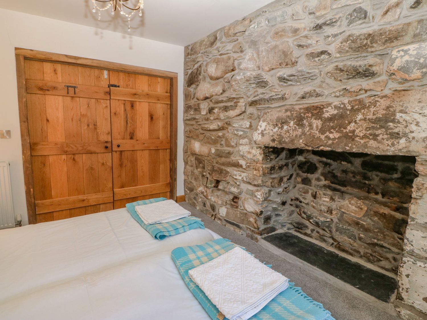 A bedroom with a stone fireplace, wooden wardrobe, and neatly folded towels.