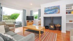 A living room with a fireplace, a television, and a bookshelf. - Bryher (Wadebridge)