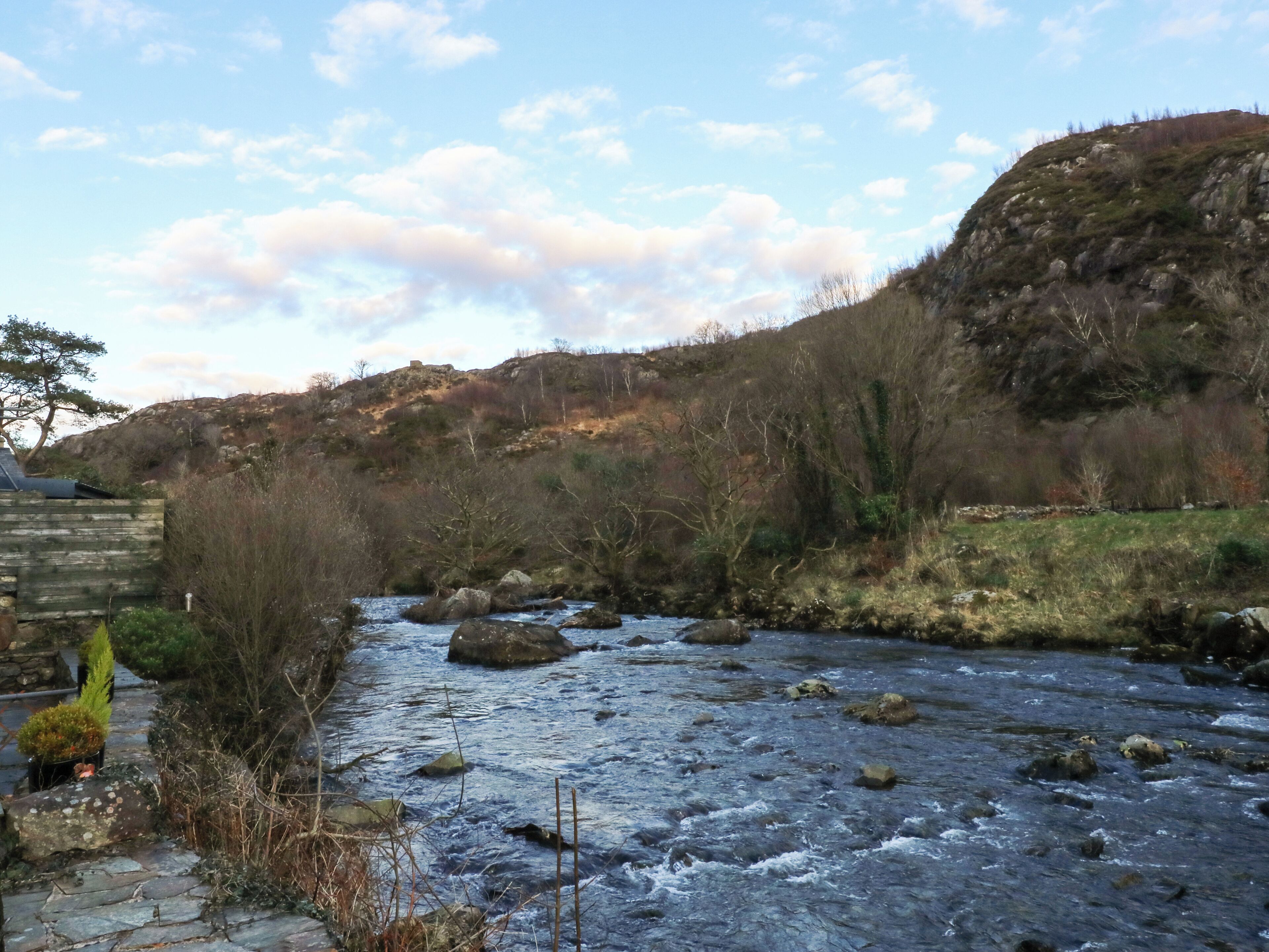 A river flowing through a rocky landscape with a stone pathway on the left.