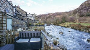 Una terrazza sul fiume con posti a sedere, muri in pietra e vista sul fiume e sulle colline.