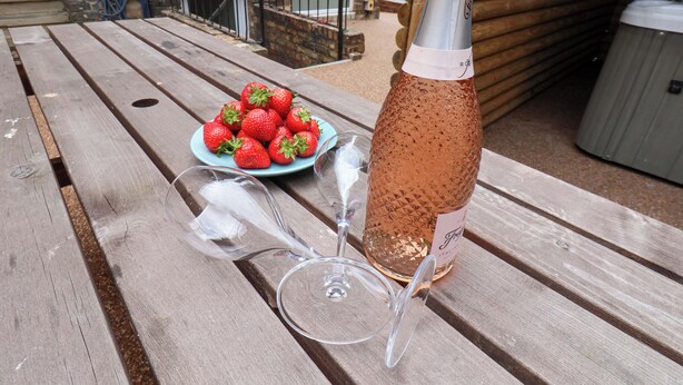 A picnic table with a plate of strawberries, a bottle of champagne, and two wine glasses. - The Corner House (Scarborough)