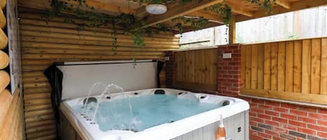 Un jacuzzi con chorros de agua, rodeado de paredes de madera y una pared de ladrillo.