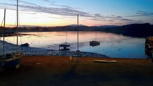 Un paysage paisible au bord de l’eau, avec des bateaux amarrés et un ciel dégagé.