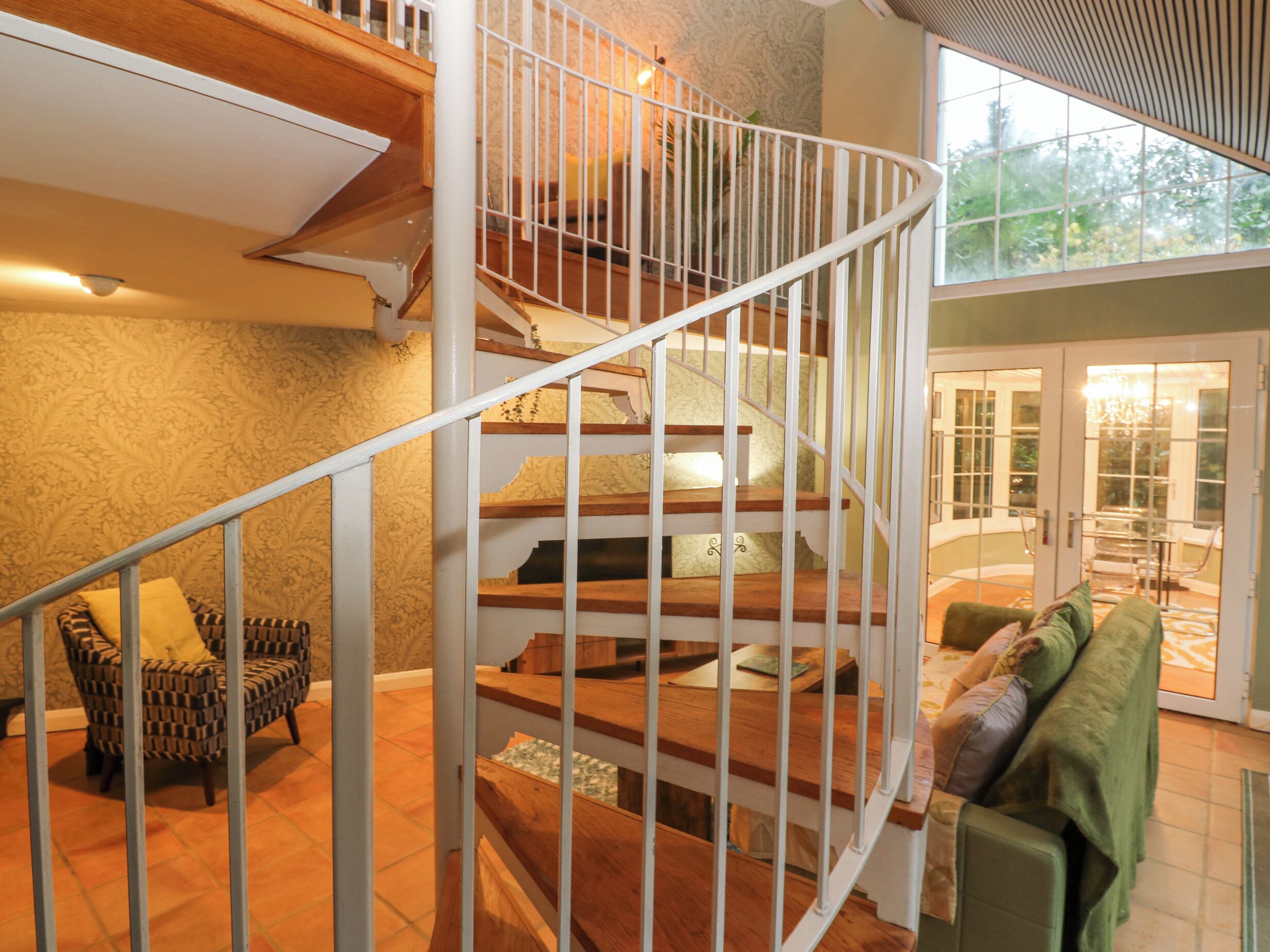 A spiral staircase with wooden steps and white railings, leading to an upper floor.