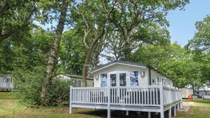 A small, single-story mobile home with a white exterior and a covered porch.