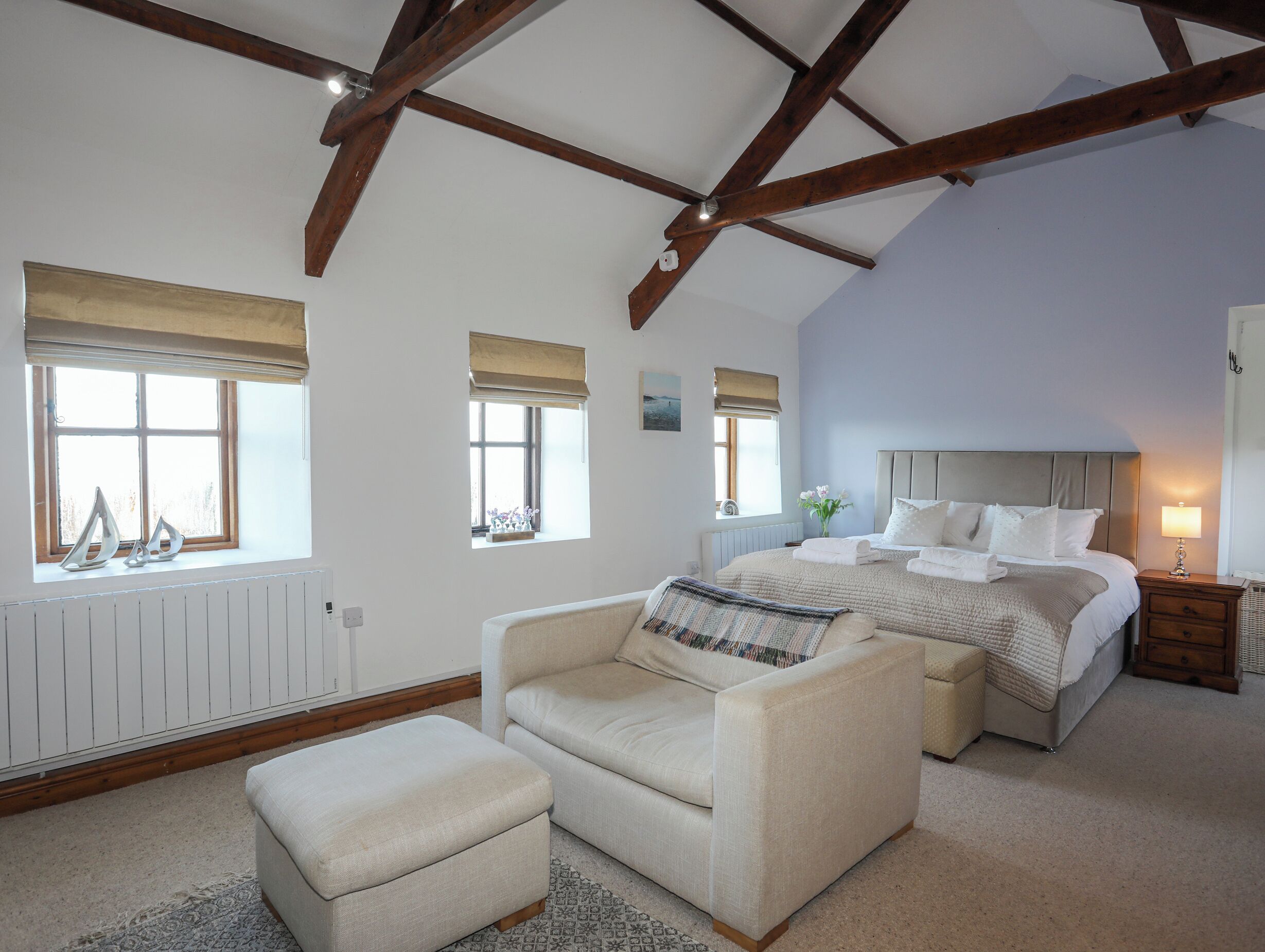 Un dormitorio con una cama grande, una silla, una mesita y una ventana con vistas.