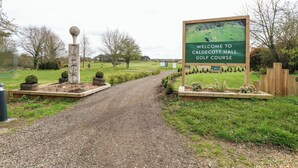 Un camí de grava que condueix a l'entrada d'un camp de golf, amb un cartell de benvinguda.
