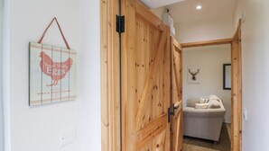 A wooden door leading to a room with a bed and a wall-mounted picture of a rooster. - B&B 3 (Saffron Walden)