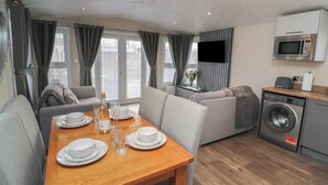 A compact living space with a dining area, sofa, and kitchenette. - 24 Sherwood (Carnforth)