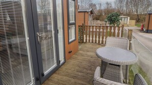 A covered patio with wicker furniture, a wooden deck, and a view of the surrounding area. - 24 Sherwood (Carnforth)