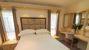 A neatly arranged hotel room with a large bed, a desk, and a chair.