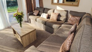 A living room with a sectional sofa, a wooden coffee table, and a large mirror on the wall.
