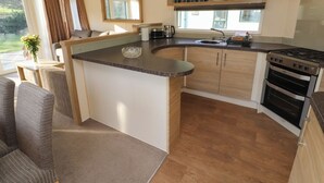 A compact kitchen with a central island, wooden cabinets, a built-in oven, and a window providing natural light.