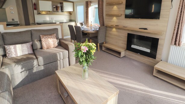 A modern living room with a sofa, a coffee table, a fireplace, and a TV mounted on the wall.