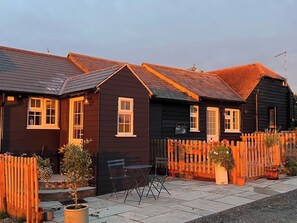 A row of dark-colored houses with a wooden fence and potted plants. - B&b 1 (Saffron Walden)