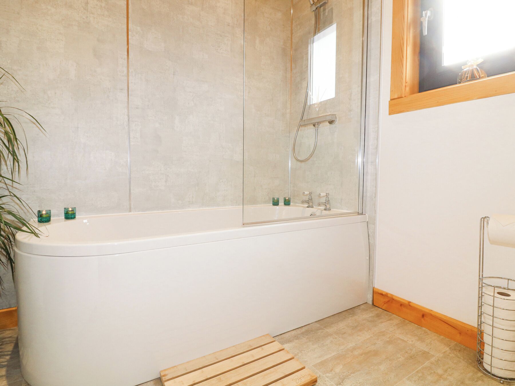 A bathroom with a freestanding bathtub, a glass-enclosed shower, and a wooden bench.