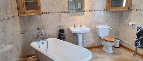 A bathroom with a freestanding bathtub, a sink, a toilet, and wooden cabinets.