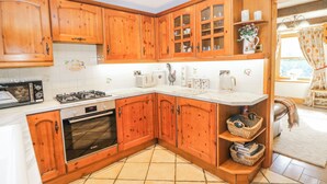 A kitchen with wooden cabinets, a Bosch oven, a microwave, and a coffee maker. - Brook Cottage (High Peak)