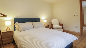 Une chambre à coucher avec un lit, deux lampes de chevet, une chaise et un plancher en bois.