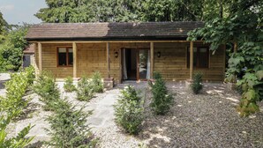 Une cabane en bois dotée d’un porche, entourée de gravier et de petites plantes.