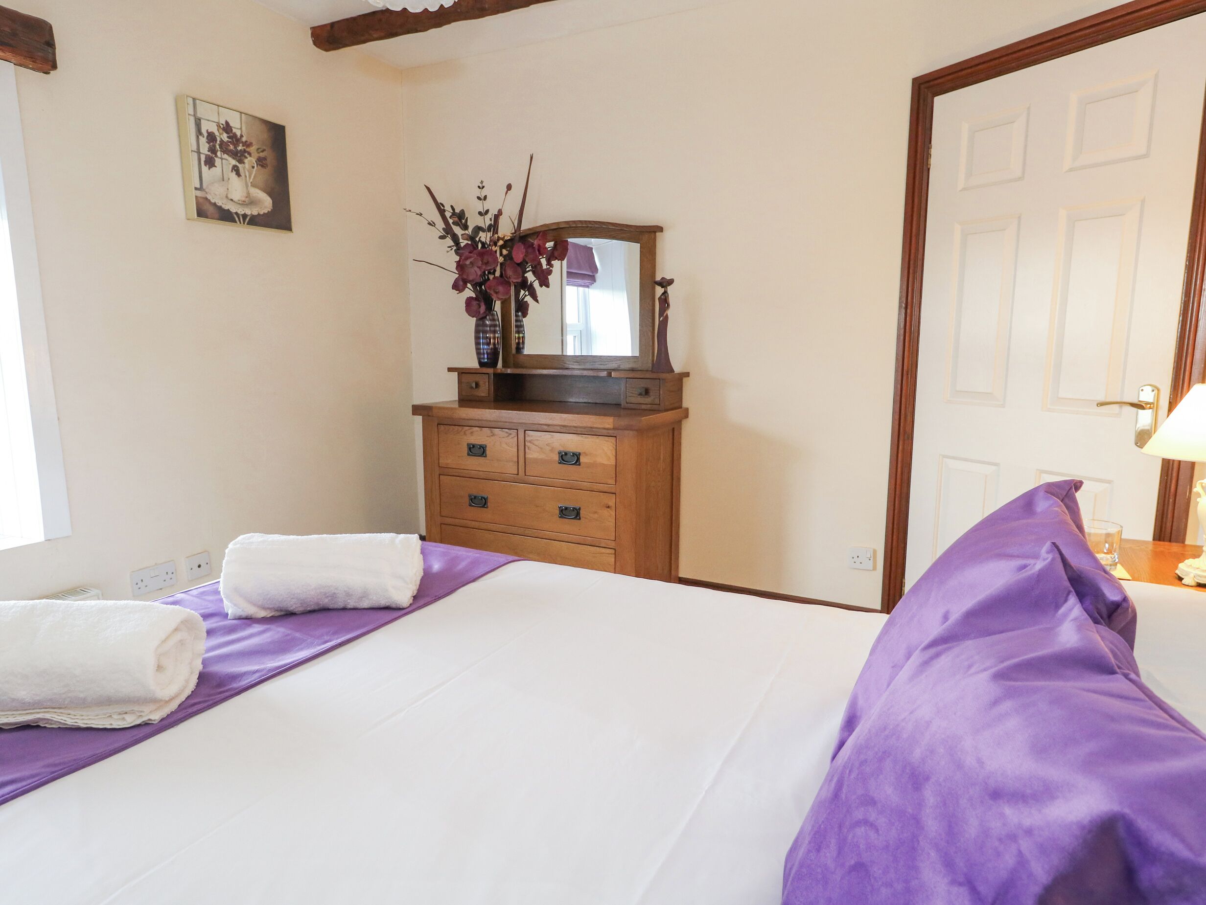 A hotel room with a bed, a dresser, a mirror, and a window.