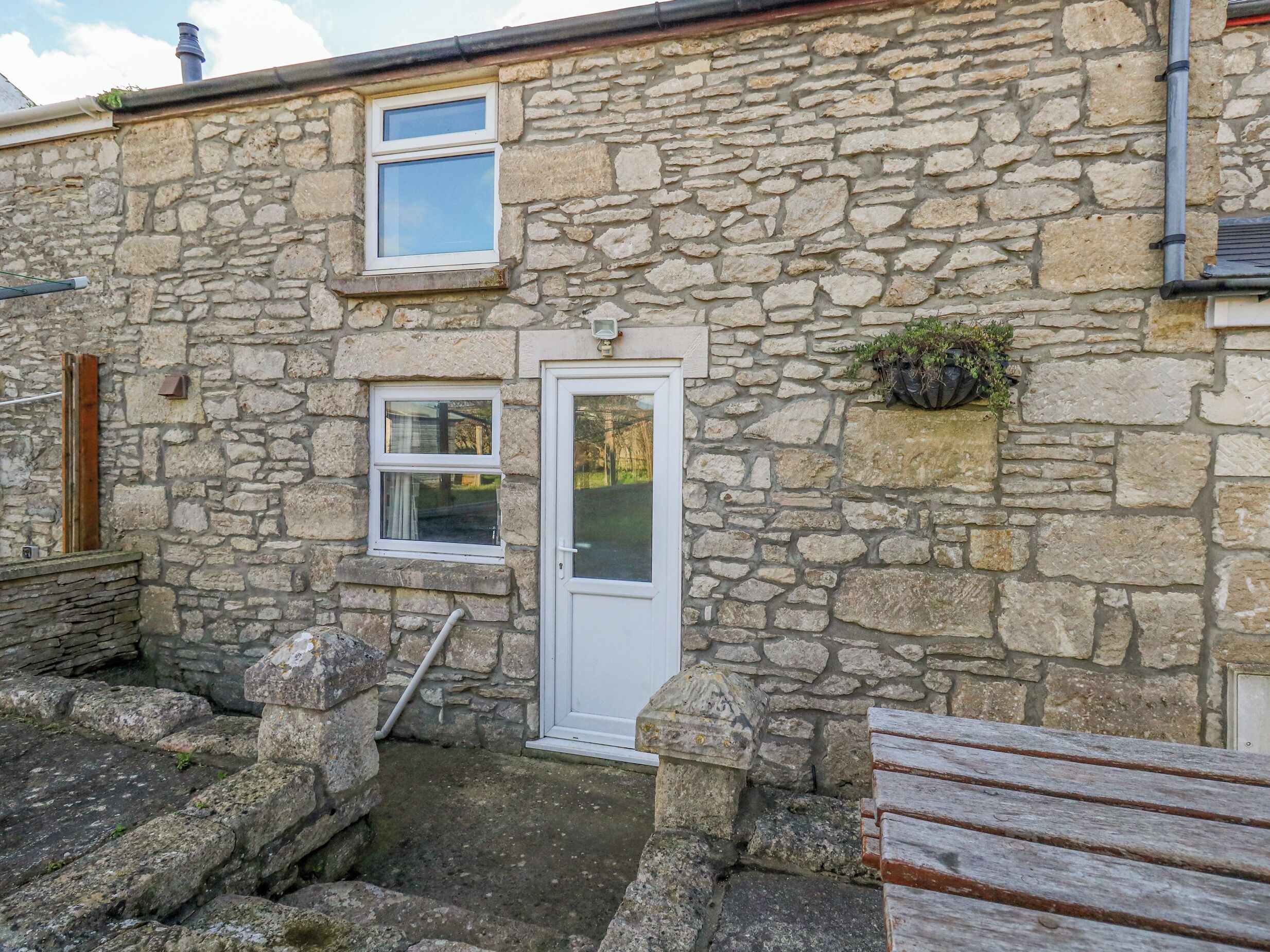 A stone building with a white door, two windows, and a small garden area.