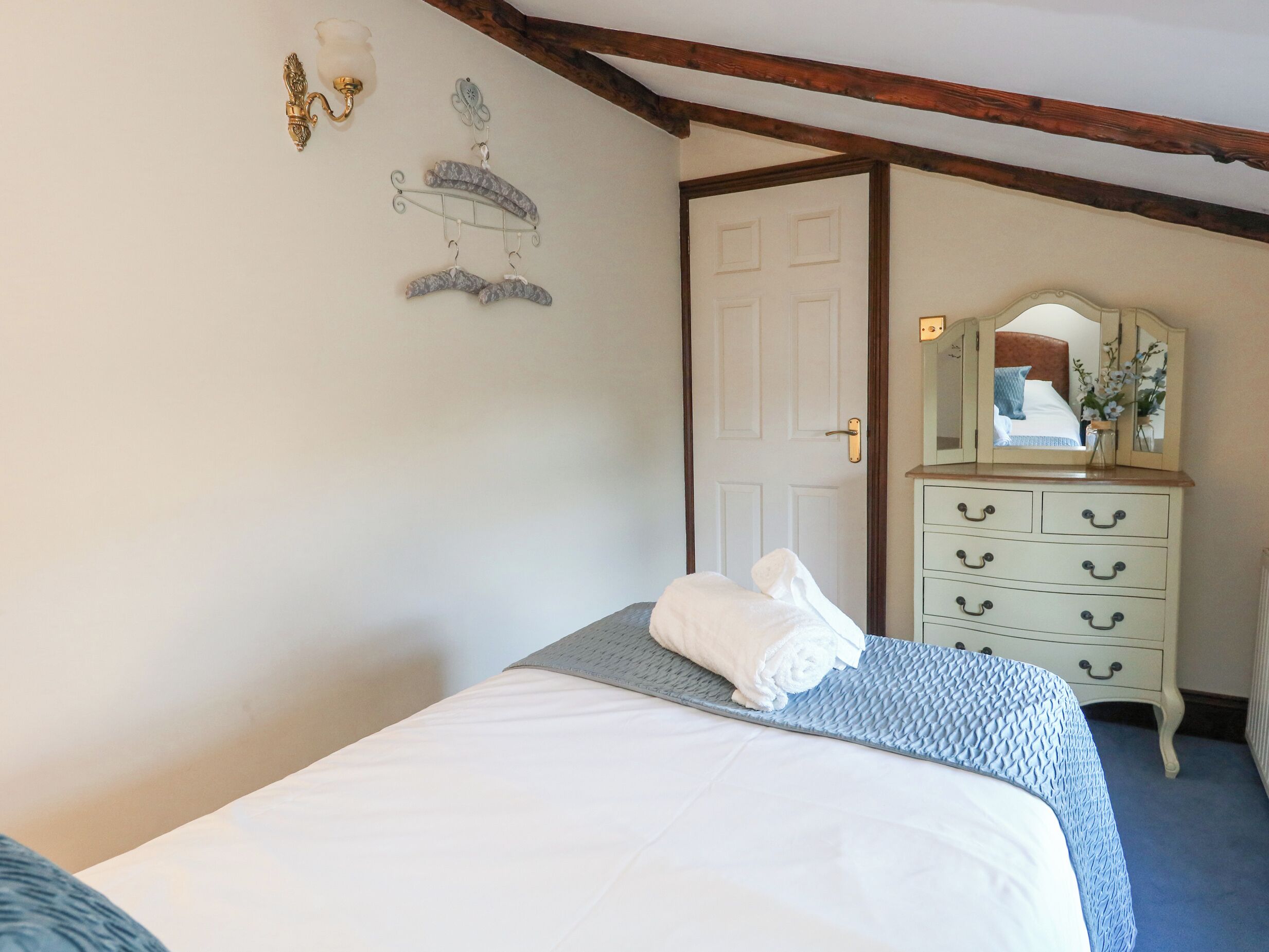 Une chambre à coucher comprenant un lit, une commode, un miroir et un élément de décoration fixé au mur.