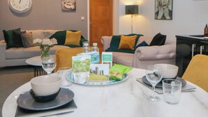 A dining area with a table set for two, featuring a bowl, glasses, and a plate with a box of biscuits. - Number 4 Westmoreland (Matlock)