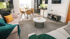 A modern living room with a sofa, coffee table, and a dining area with chairs. - Number 4 Westmoreland (Matlock)