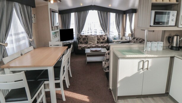Un espacio habitable compacto con comedor, sofá, kitchenette y televisor.