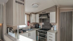 Una cocina compacta con armarios de madera, una estufa a gas, un fregadero y un horno pequeño.