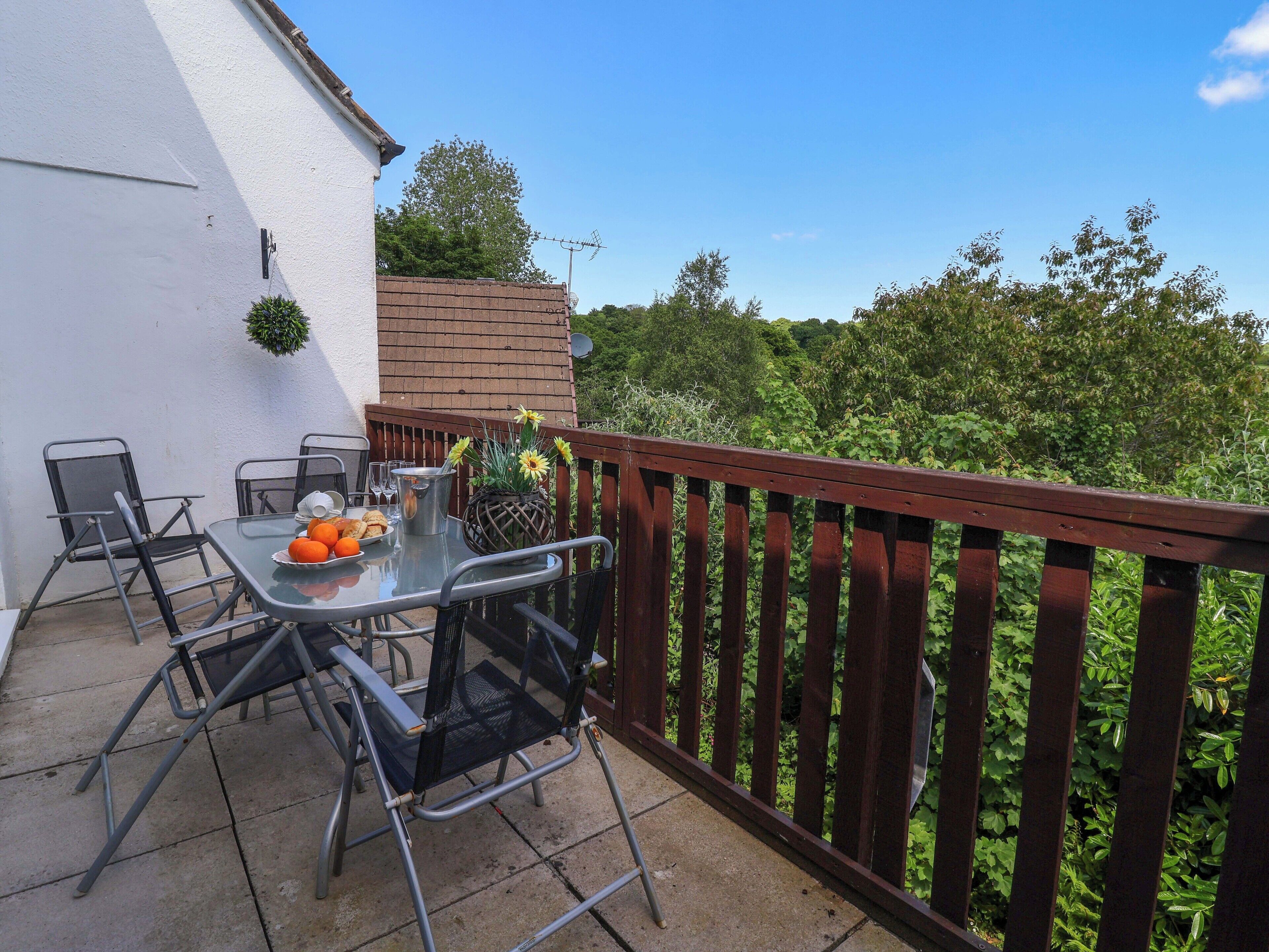 An outdoor patio with a table set for two, surrounded by metal chairs.