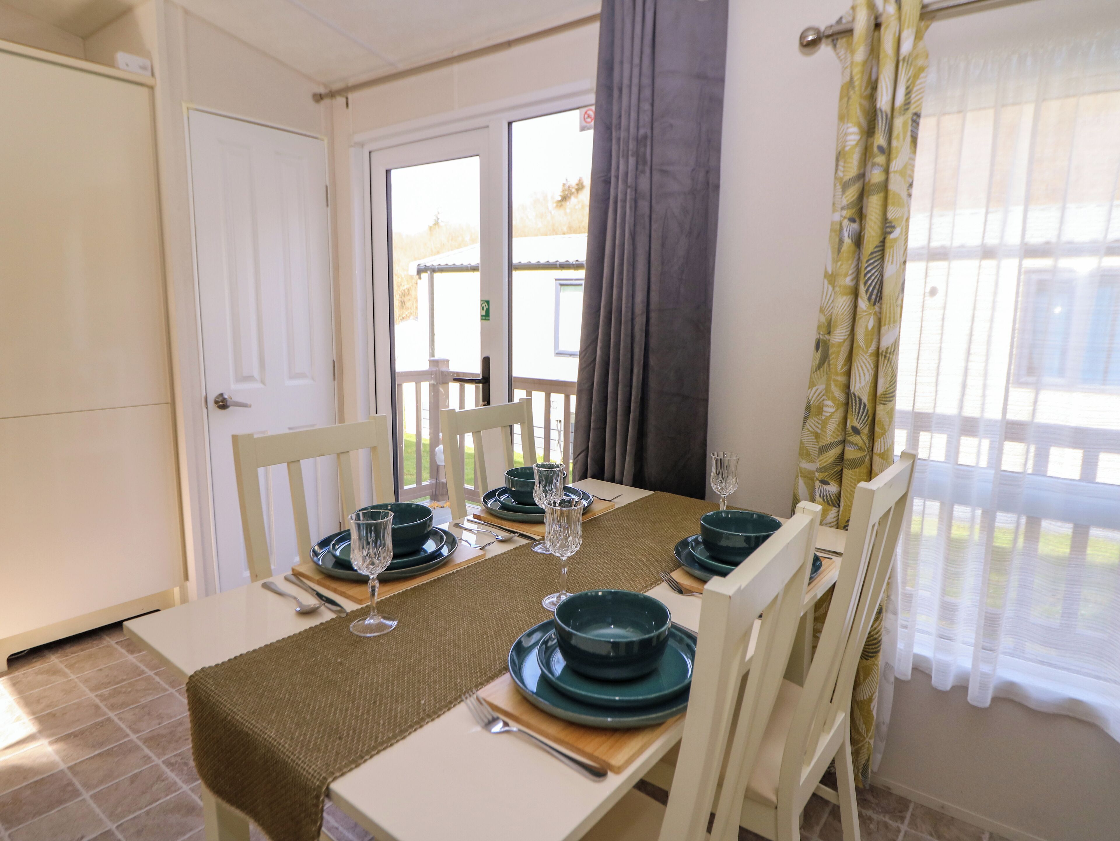 Uma sala de jantar com uma mesa posta para quatro pessoas, incluindo pratos, tigelas e copos de vinho.